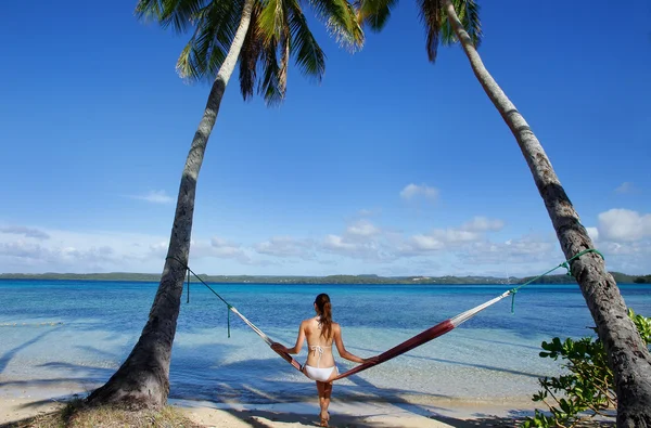 Ey palmiye ağaçları arasında bir hamakta oturmuş bikinili genç kadın — Stok fotoğraf