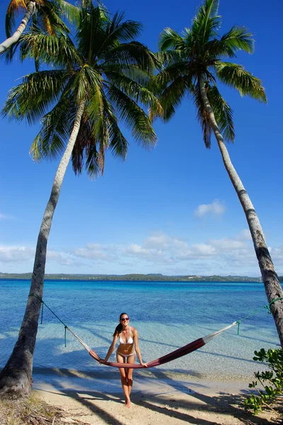 Jovem de biquíni em pé junto à rede entre palmeiras — Fotografia de Stock