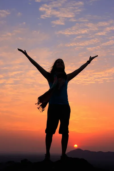 Sillouetted vrouw met haar armen omhoog bij zonsondergang op de top van de heuvel, — Stockfoto