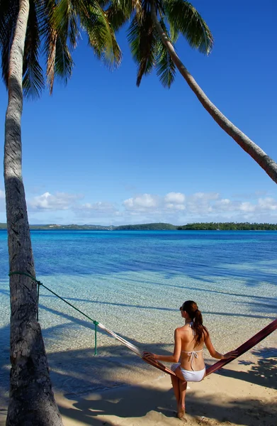 Jonge vrouw in bikini zittend in een hangmat tussen palmbomen, o — Stockfoto