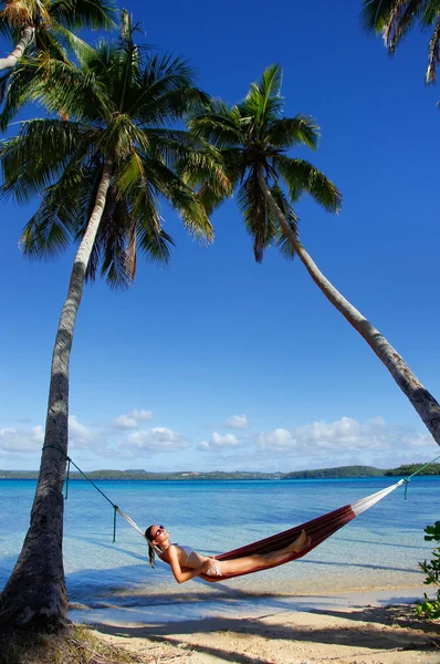 Jonge vrouw in bikini in een hangmat tussen de palmbomen, het leggen van — Stockfoto