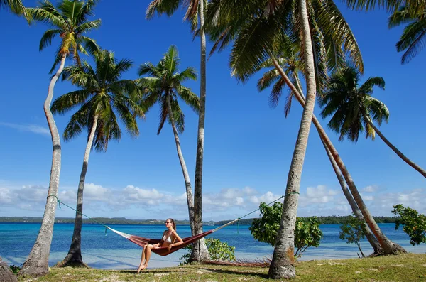 Młoda kobieta w bikini siedzi w hamaku pomiędzy palmami, o — Zdjęcie stockowe