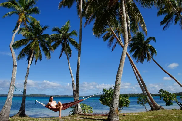Mujer joven en bikini sentada en una hamaca entre palmeras, O — Foto de Stock