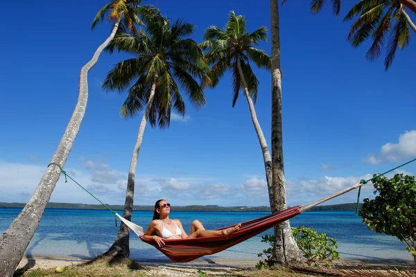 Jonge vrouw in bikini zittend in een hangmat tussen palmbomen, o — Stockfoto