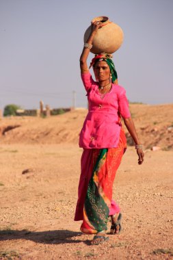Local woman carrying jar with water on her head, Khichan village clipart