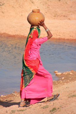 Local woman carrying jar with water on her head, Khichan village clipart