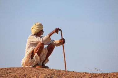 Local man sitting on a hill, Khichan village, India clipart