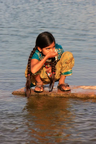 Local girl drinking from water reservoir, Khichan village, India — Stock Photo, Image