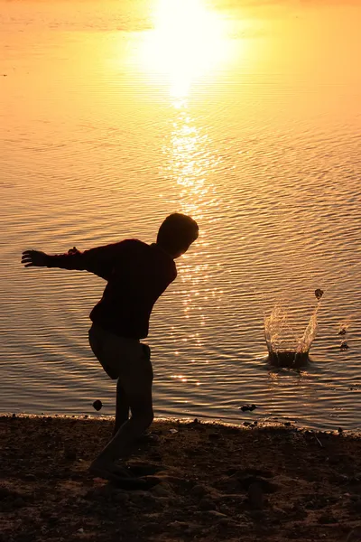 Silhouette of a boy throwing stones in a water, Khichan village, — Stock Photo, Image