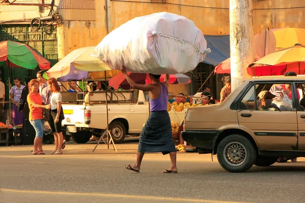 地元の男性と彼の頭、ヤンゴン、myanm 上で商品の大きな袋を運ぶ — ストック写真