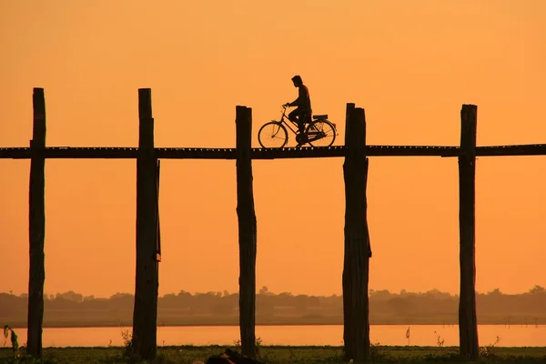 Silhouet persoon op met een fiets op u bein brug bij zonsondergang, ben — Stockfoto