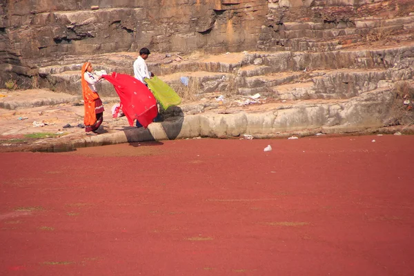 Indian women in colorful saris standing at the edge of red pond, — Stock Photo, Image