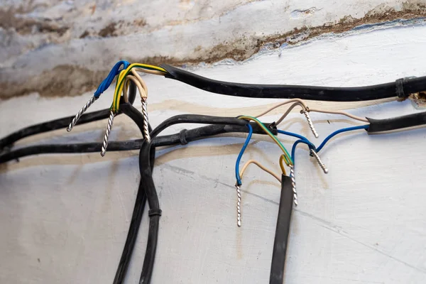 Connection of wires against the background of a wall in a house under construction. Twisting, soldering, welding of electrical cables