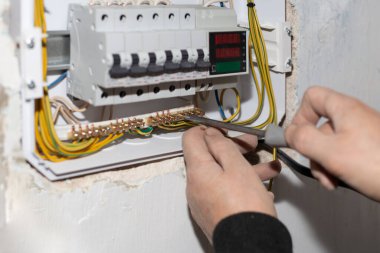 Elektrik santrali mi? Bir elektrikçi evin duvarına elektriği kontrol etmek için çok işlevli bir kalkan yerleştirir.