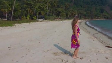 Okyanusun kumlu sahilinde uzun sarı saçları olan bir kadın. Mutlu deniz tatili