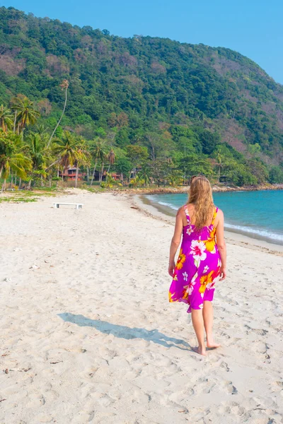На піщаному березі серед пальм на тропічному острові Таїланду ходить жінка з довгим світлим волоссям. — стокове фото