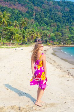 Uzun sarı saçlı bir kadın Tayland 'daki Koh Chang adasında kumlu sahil boyunca yürüyor. Seyahat ve turizm.