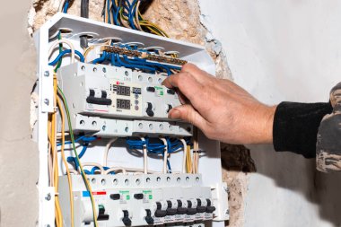 Rusya, Anapa-07.2020: Elektrikçi evin duvarına inşa edilen elektrik panelinin anahtarlarını açıyor. Elektrik kontrol aygıtı.