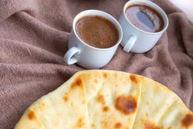 İki fincan kahveyle bir masada süzme peynirle doldurulmuş ev yapımı taze düz ekmek.