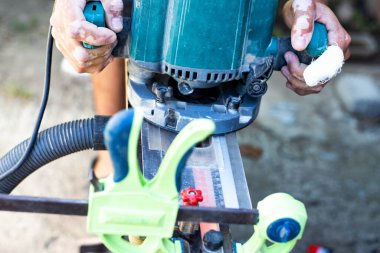 Vitiligo lekeleri olan bir marangozun erkek elleri değirmen makinesi tutuyor. Profesyonel araçlarla ahşap işleme.