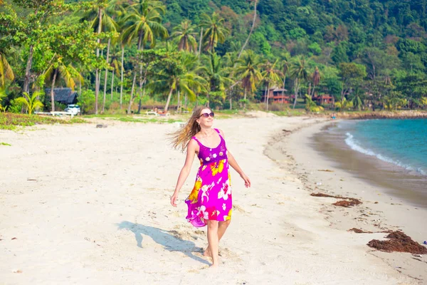 Доросла блондинка в яскравій сукні на тропічному узбережжі посміхається. Подорожі та туризм — стокове фото