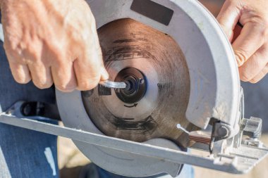 Adam, ahşap işçiliği için elektrikli testere testeresine altıgen ile testere vidalıyor..