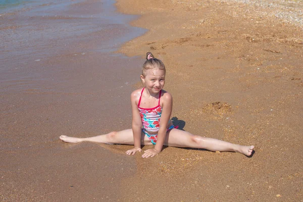 Ein Kleines Mädchen Sitzt Einem Sandigen Meeresufer Einem Quer Verlaufenden lizenzfreie Stockbilder
