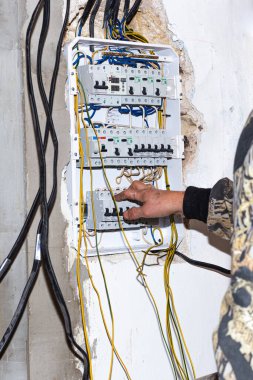 Bir elektrikçi eve bir elektrik paneli kuruyor. Elektriği iletiyor, açıyor ve koruyor. Rusya, Anapa - 11.07.2020