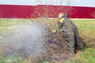 Baharda kurumuş ağaç dalları yakmak. Bahçeyi temizliyorum. Bir adam birkaç dalı ateşe verdi.
