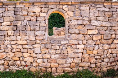 old stone wall with arched window opening