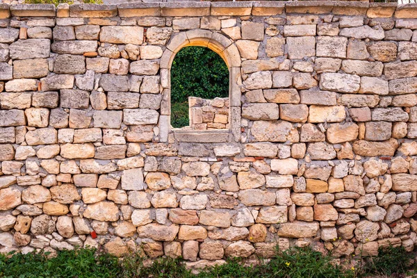 old stone wall with arched window opening