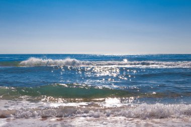 A beautiful sparkling blue sea splashes on the horizon with blue skies. Seascape, natural background.