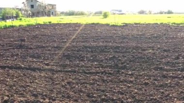 Güneşli bir bahar gününde, bir bahçe arazisinde sürülen bir tarla. Kablolar soldan sağa