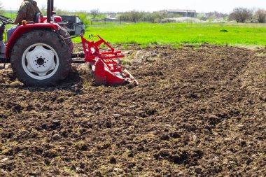 Küçük bir traktör bahçedeki araziyi sürüyor. Tarım ve Tarım.