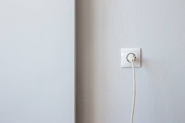 Elektrik prizinde kabloyla, kopyalanmış gri duvarın karşısında. Elektrik tüketimi.