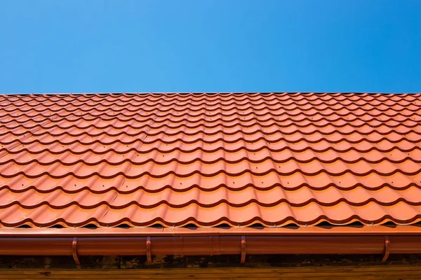 Metal tile roof and downpipe gutter. Construction and repair of the house.