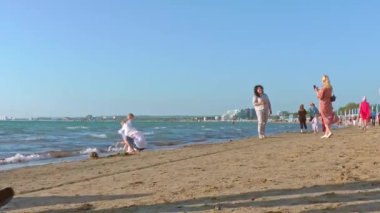 Turistler güneşli bir yaz gününde deniz kıyısında yürürler. Seyahat ve turizm.