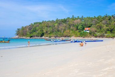 Tropikal bir adada deniz plajı. İşçiler, turistler için teknelerde panton yapıyorlar. Tayland, Phuket, Kata plajı - 22.02.2022