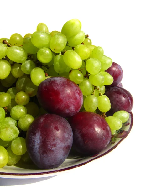 Зелений виноград і сливи на тарілці ізольовані на білому тлі c — стокове фото