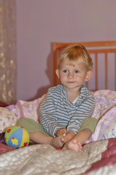 Ребенок сидит на кровати и наблюдает — стоковое фото