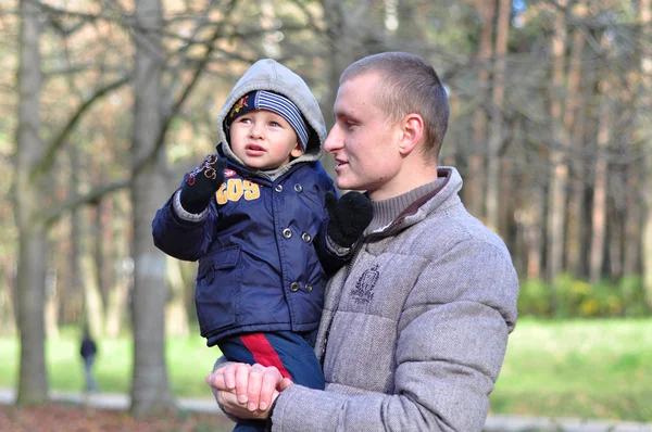 ลูกชายตัวน้อยดูประหลาดใจ นั่งอยู่ในมือของพ่อ — ภาพถ่ายสต็อก