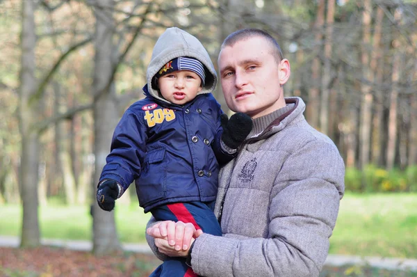 Küçük çocuk ve baba parkta başına oturan oğlu yürümek için — Stok fotoğraf