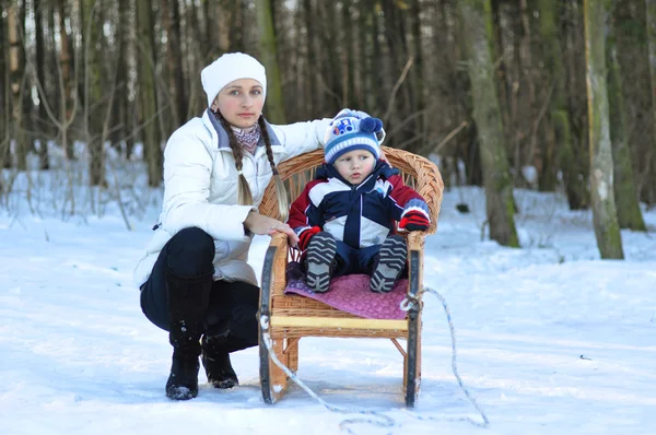 Young mother and child on a winter walk in the park and ride on — Stock Photo, Image