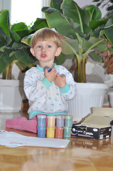 Веселый ребенок играет с краской готовясь рисовать

