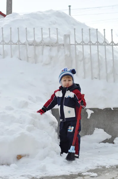 Little boy with brush on a snowy landscape — Stock Photo, Image