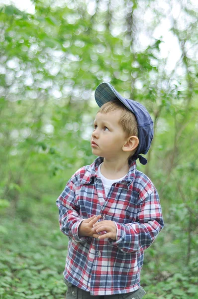 Il ragazzo nel parco distoglie lo sguardo su sfondo verde sfocato — Foto Stock