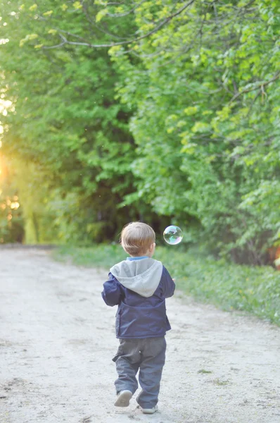 Enfant marchant sur le sentier par des bulles de savon dans le parc — Photo