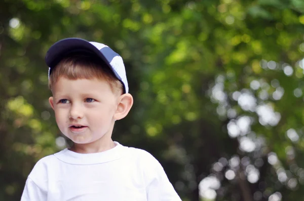 A little boy closeup on a background of green leaves — Stock Photo, Image