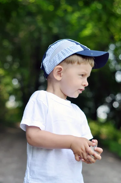 Little boy holding stones close up on a background of green leav — Stock Photo, Image