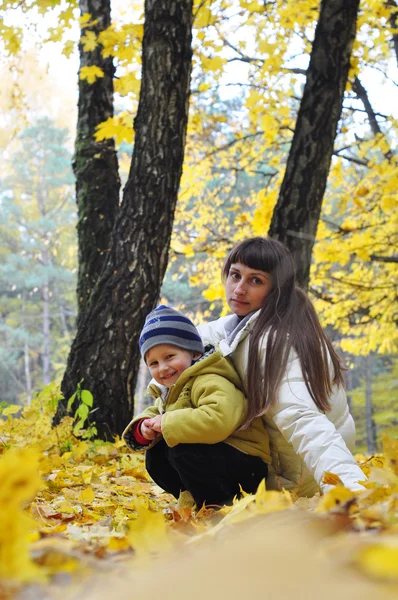 Uśmiechający się matką i dzieckiem na spacer w parku, jesień le żółty — Zdjęcie stockowe